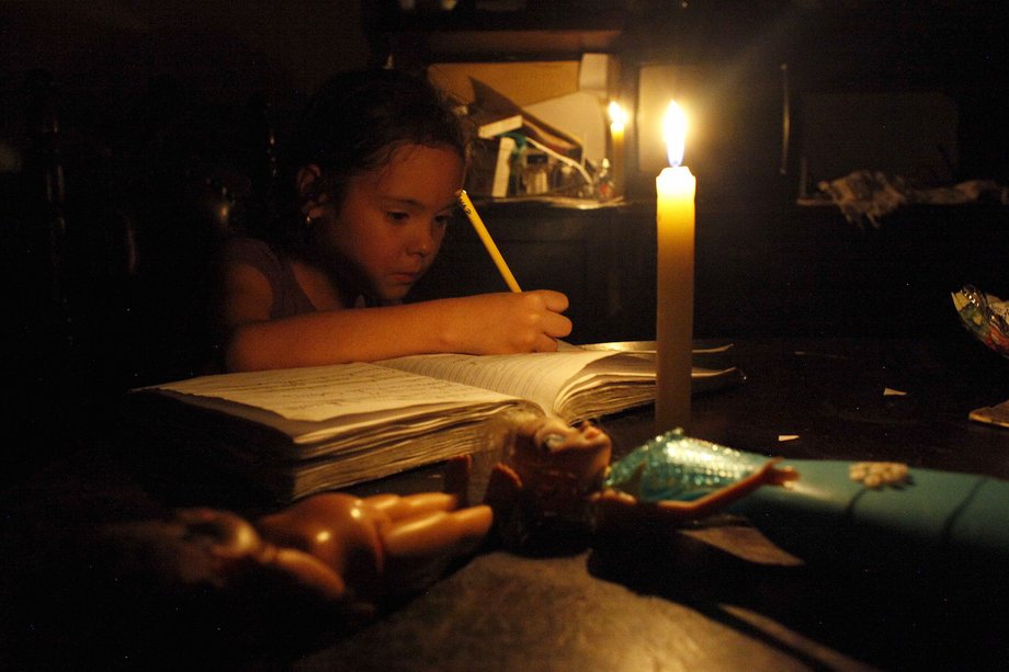 A girl does her homework by candlelight at her home during a power cut in San Cristobal, in the state of Tachira, Venezuela, April 25, 2016.