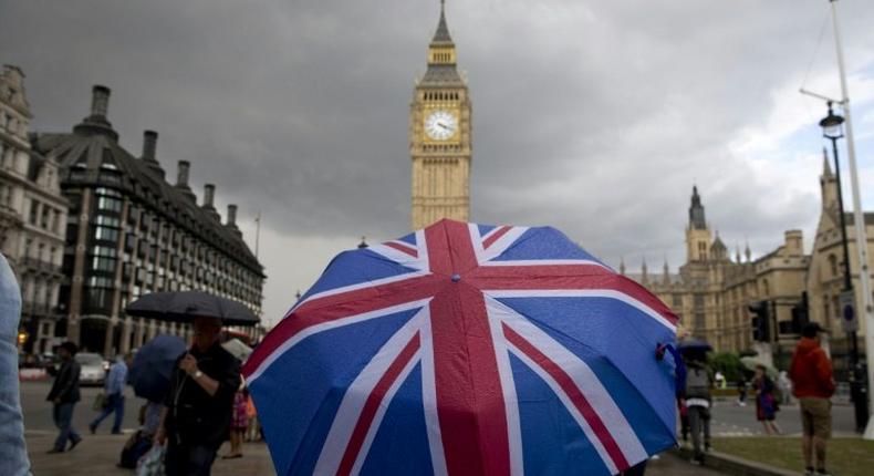 A pedestrian shelters from the rain near the Big Ben clock on June 25, 2016, following the result of the UK's EU referendum vote