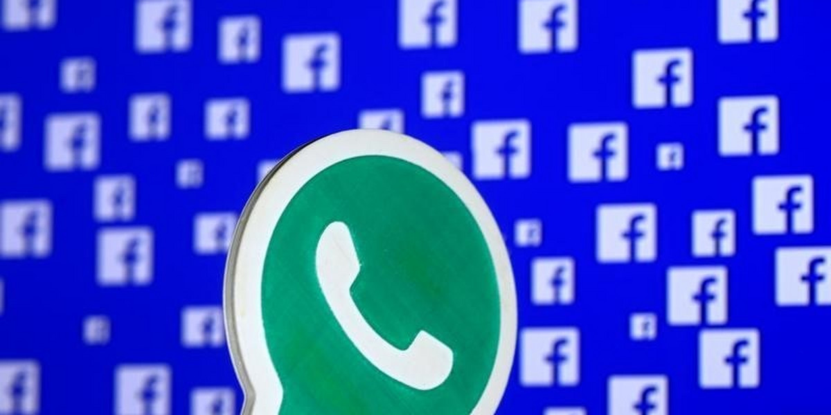 A 3D-printed WhatsApp logo is seen in front of a displayed Facebook logo in this illustration.