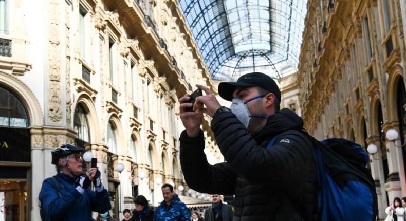 A man wearing a protective facemask takes pictures at the Gallery Vittorio Emanuele II in Milan on Monday