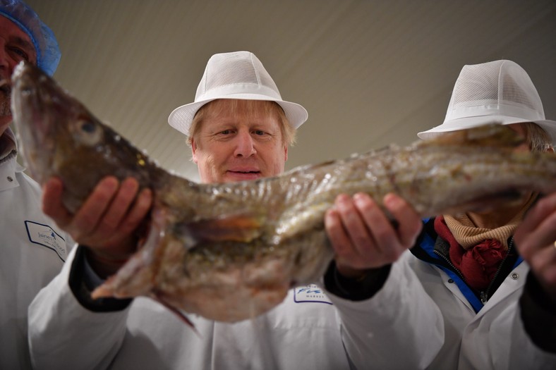 Ówczesny premier Wielkiej Brytanii i lider Partii Konserwatywnej Boris Johnson pozuje z dorszem podczas wizyty w Grimsby w północno-wschodniej Anglii, 9 grudnia 2019 r.