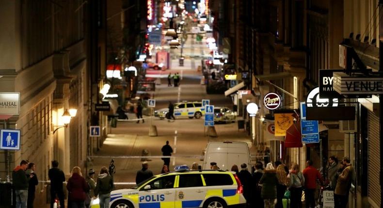 People stand behind a cordon as police work at the scene of a truck attack that killed four people outside a busy department store in central Stockholm on April 7, 2017