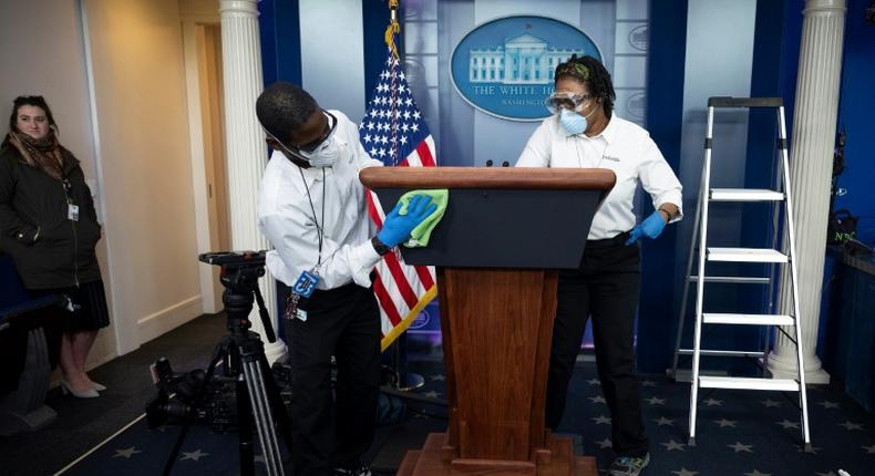 Cleaning staff disinfect the lectern in the White House Press Briefing Room