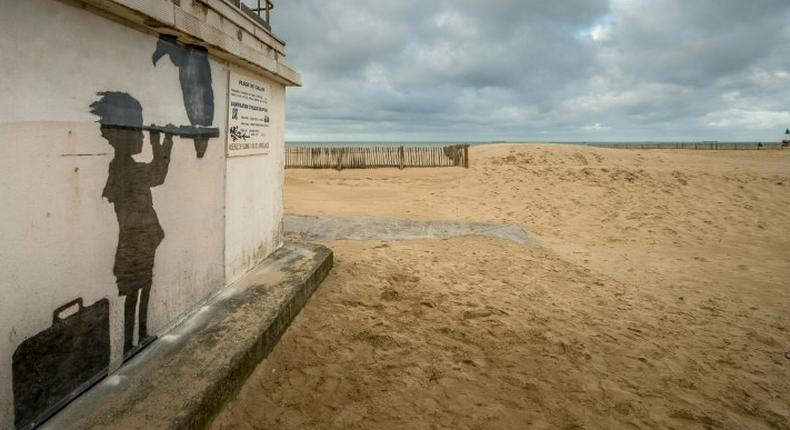 An art piece protected by a plexiglass pane by British artist Banksy, seen on a beach in Calais, northern France