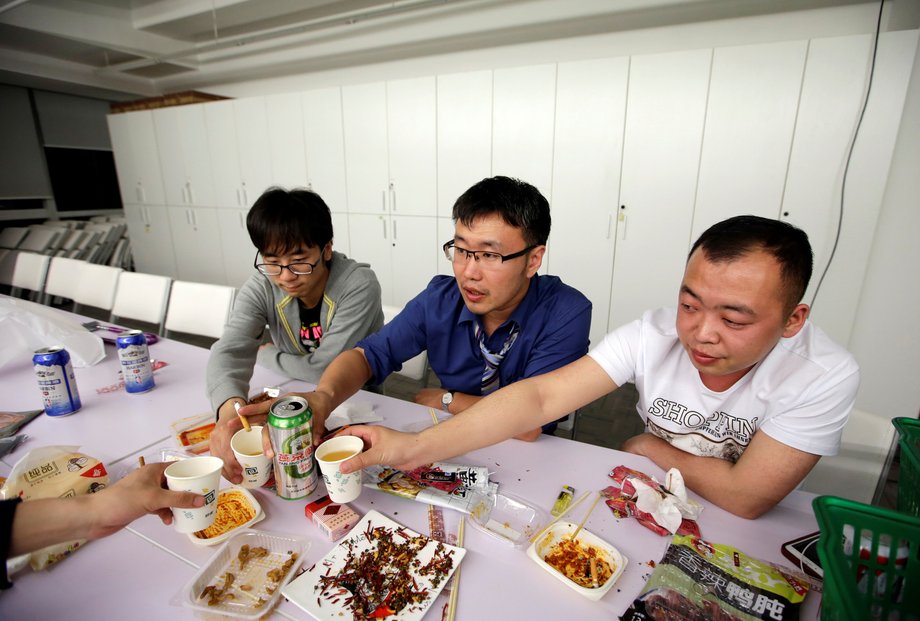 With so many hours in the office, meals are often shared between coworkers. Here, employees of RenRen Credit Management Co. drink and eat after finishing work past midnight.