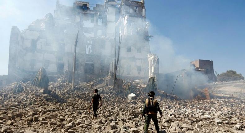 Huthi rebel fighters inspect the damage after a reported air strike by the Saudi-led coalition in Sanaa in December 2017