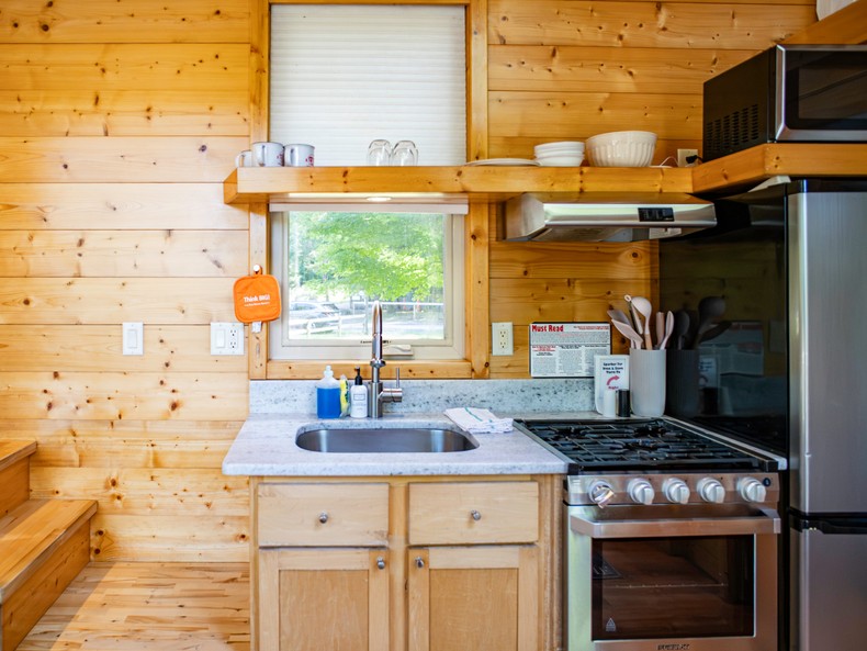 Although it was small, the kitchen had everything I'd need to cook: a full-sized fridge, a small oven with a stovetop, and a deep sink. Above the fridge, a wide shelf stored a microwave and dishware.Across from the sink, a rolling mini bar stored a coffee maker, a toaster, a toaster oven, and utensils.