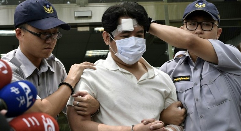 A man identified only by his family name Lu (C), is escorted by policemen after he was suspected of slashing a guard with a Samurai sword at Taiwan's Presidential Palace