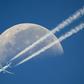 A commercial airplane flies past the moon above Geneva