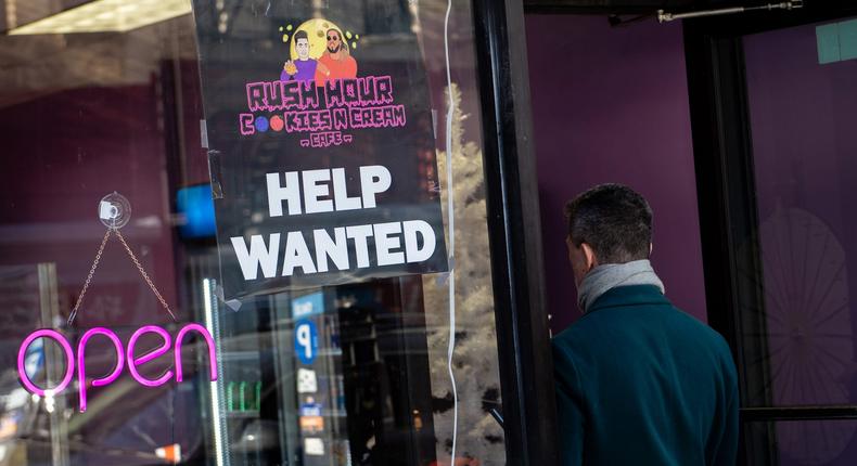 A person walks into a new cookie shop next to a Help Wanted sign on January 12, 2022 in New York City.Alexi Rosenfeld/Getty Images