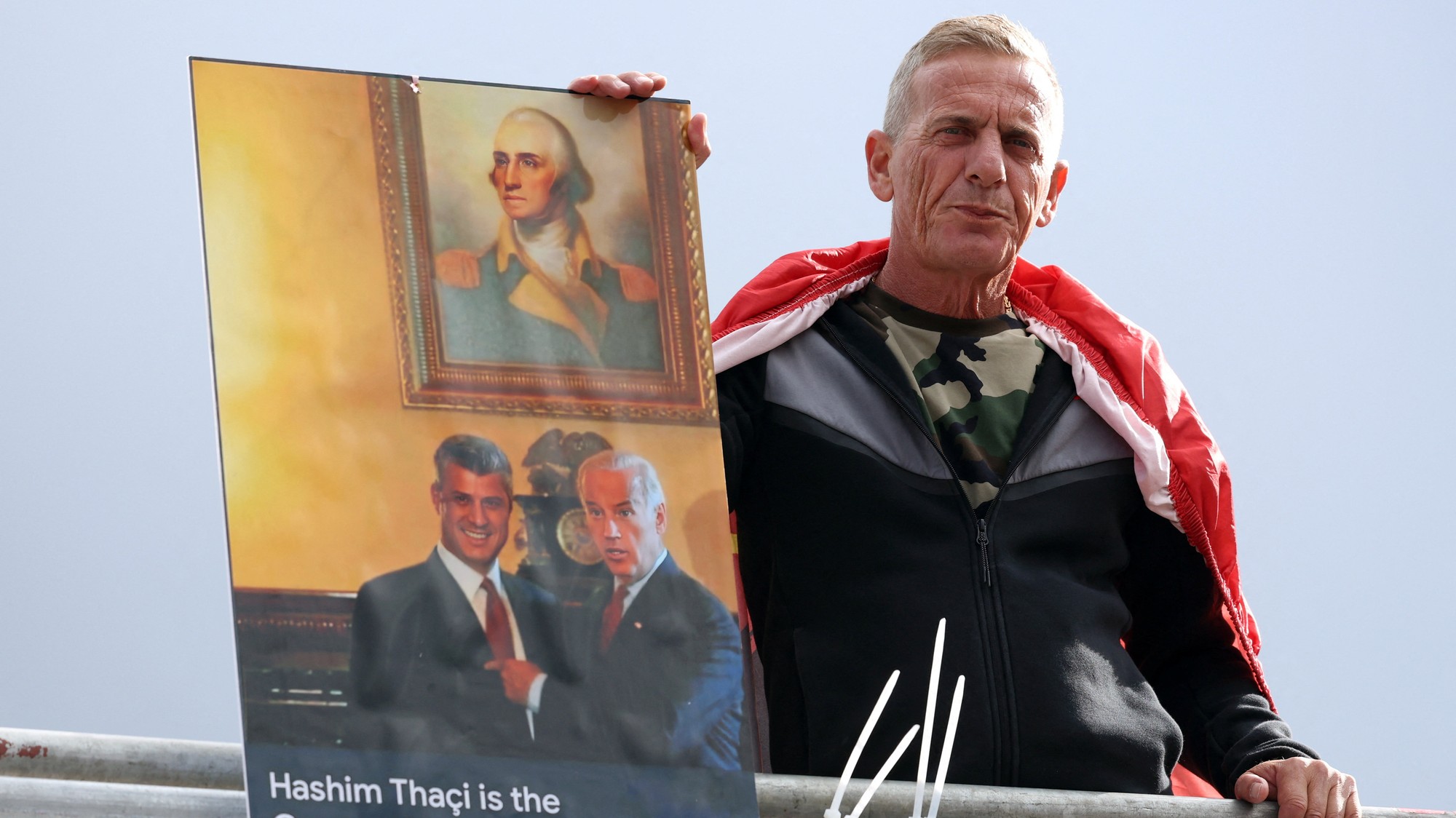 Muž protestujúci na podporu Thaciho drží fotku s jeho tvrárou