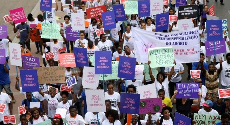 Hundreds of Angolans hold placards and shout slogans as they march to protest against a draft law that would criminalise all abortions