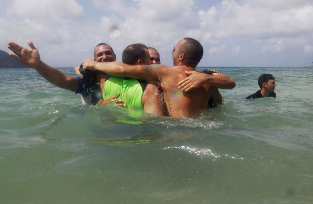 A group of Cuban migrants celebrate in the water upon arriving in a town after they crossed the bord