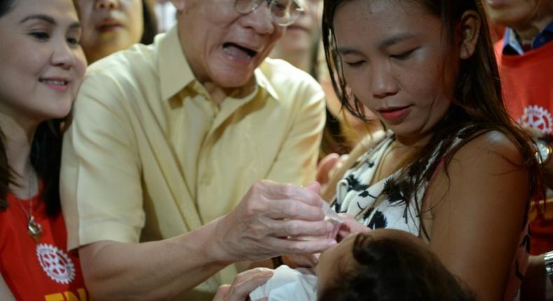 Philippine Health Secretary Francisco Duque (C) administers a dose of oral polio vaccine at the start of a programme to immunise millions of children following the country's first outbreak in nearly two decades
