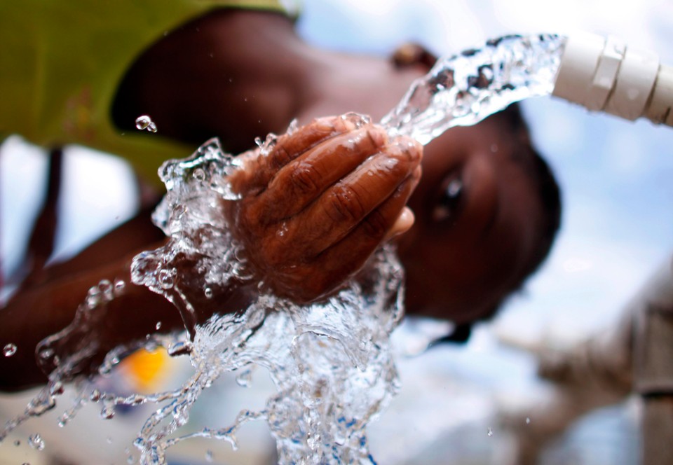 An earthquake survivor drinks water from a well in a provisional camp at downtown Port-au-Prince