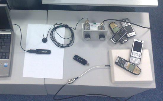 Stanowisko testowe w laboratorium Plusa: biurko, komputer, modemy, telefony, anteny i tłumik