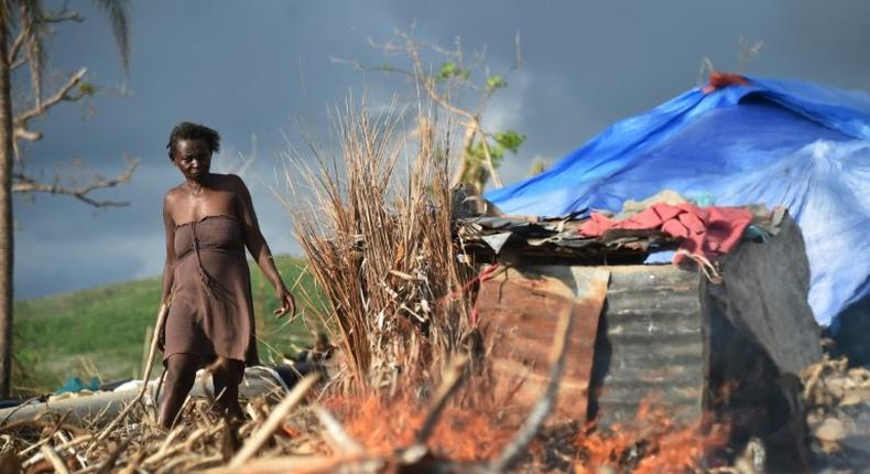 Marie walks next to her house damaged by Hurricane Matthew in the village of Labeyi, southwestern Haiti