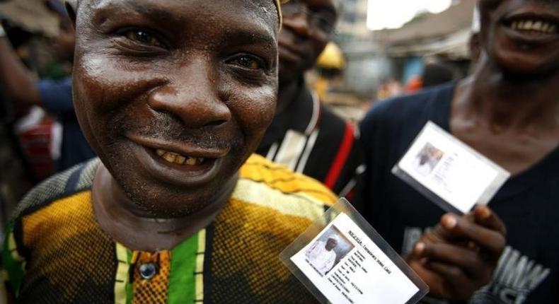 Nigerian voters show off their identity cards while lining up to vote in the neighbourhood of Isale-Eko in in a file photo. [REUTERS/Finbarr O'Reilly]