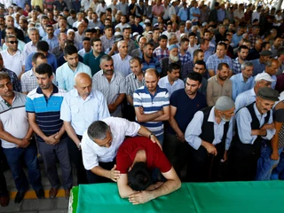 A family member of a victim of a suicide bombing at a wedding celebration mourn over a coffin during a funeral ceremony in the southern Turkish city of Gaziantep