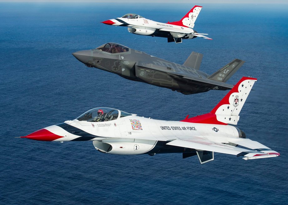 An F-35 flies at a high angle of attack relative to the US Air Force Thunderbird F-16s on either side of it.