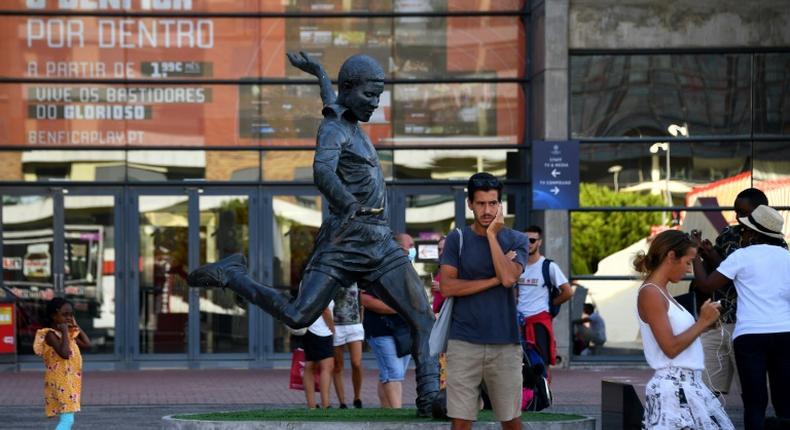 Football fans take pictures next to the statue of Portugal legend Eusebio outside Benfica's Estadio da Luz, which will host the Champions League final on August 23