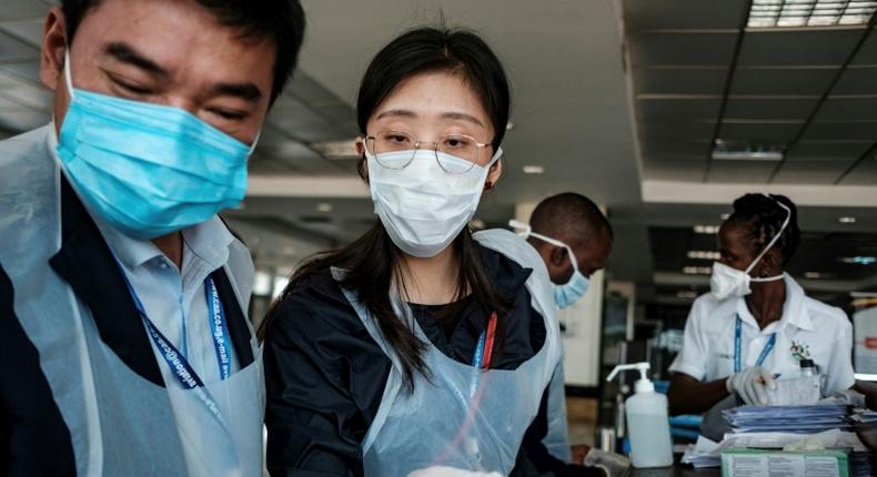 Chinese embassy officials help screen incoming passengers for the new coronavirus as they arrive at Entebbe Airport in Uganda on March 3, 2020