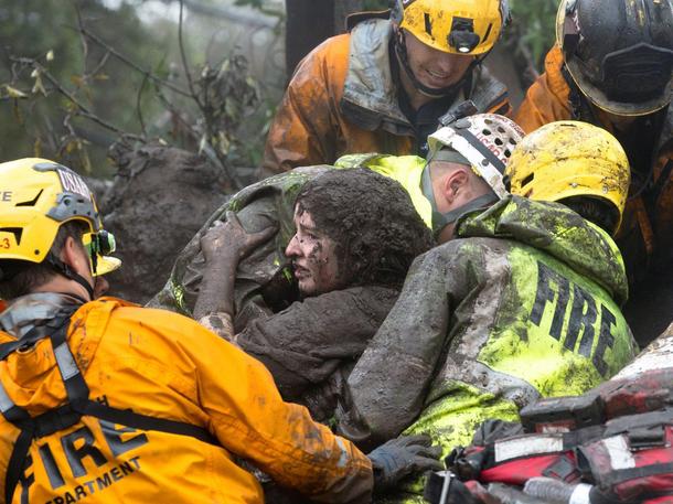 Emergency personnel carry a woman rescued from a collapsed house after a mudslide in Montecito