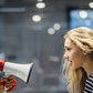 Profile view of angry female manager yelling at her colleague through megaphone.