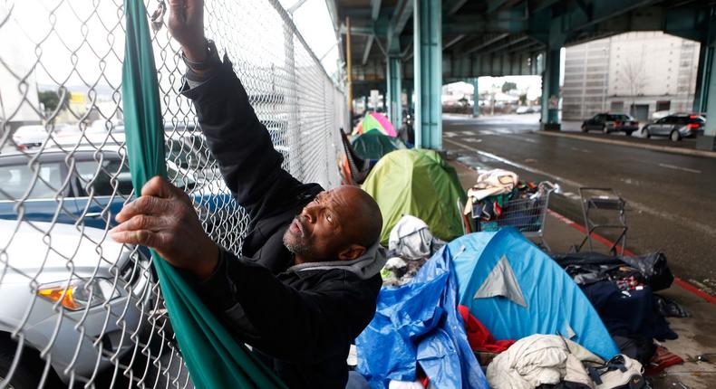 Jonathan Payne, a homeless man, takes down tarps he had used to protect his possessions during a storm in San Francisco.