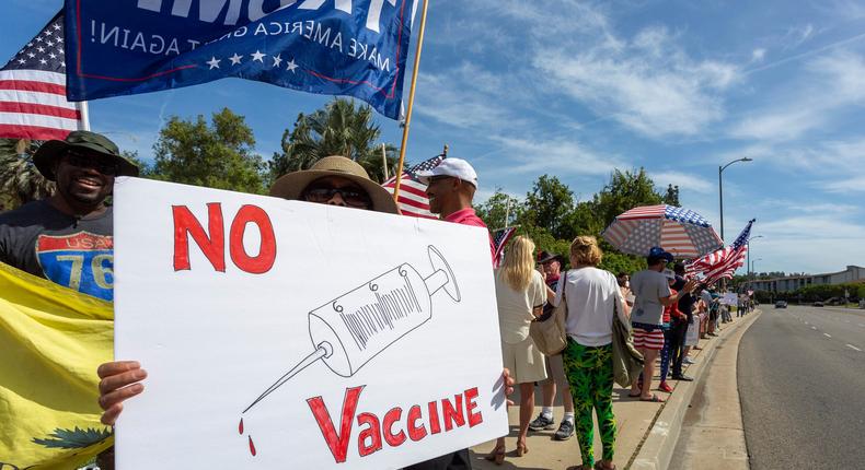 A protester holds an anti-vaccination sign as supporters of President Donald Trump rally in Woodland Hills, California on May 16, 2020.
