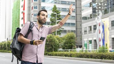 Young White Man Holding A Cellphone Hailing Uber Taxi