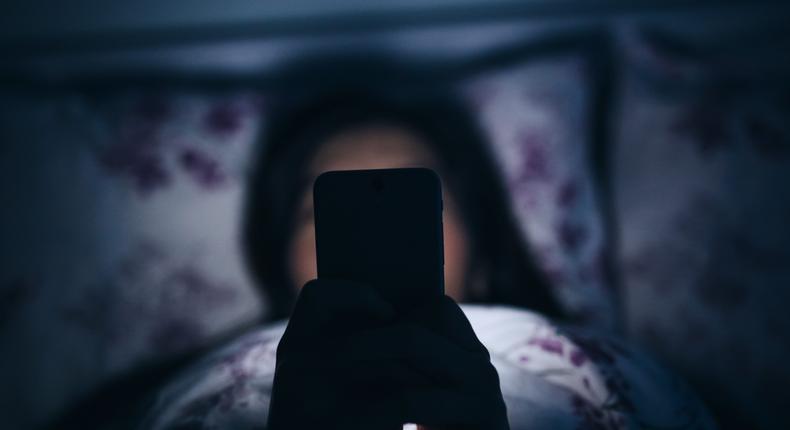 Woman reading and texting on smartphone in bed.Yiu Yu Hoi/Getty Images