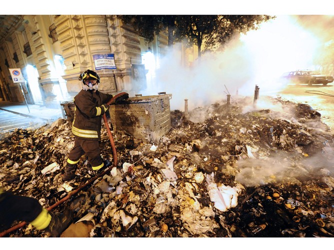 Strażak gaszący stos śmieci, jakie zasypały Neapol i inne włoskie miasta w następstwie strajków służb oczyszczania w  czerwcu 2011