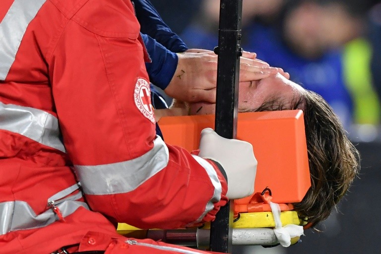 AS Roma midfielder Nicolo Zaniolo holds his face in pain as he is stretchered off against Juventus.