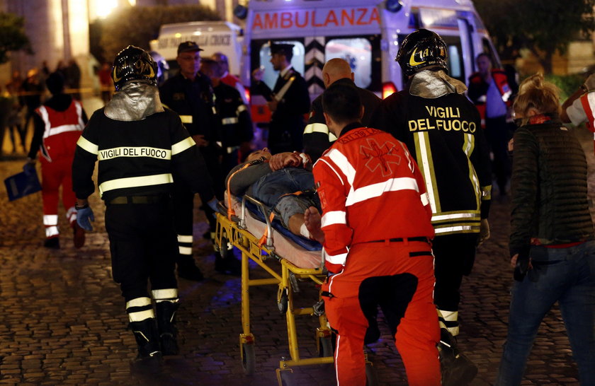 Fire fighters and medical staff member carry an injured person outside the underground where some of