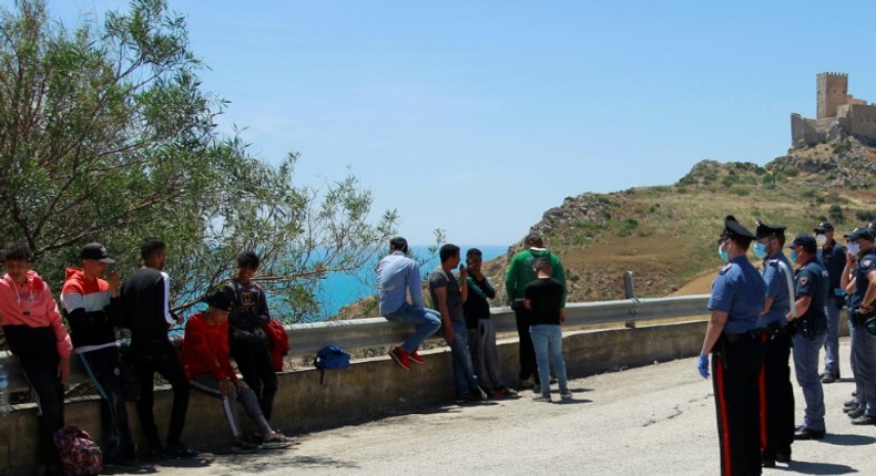 Police are shown checking and detaining some of the migrants, who left the beach in small groups