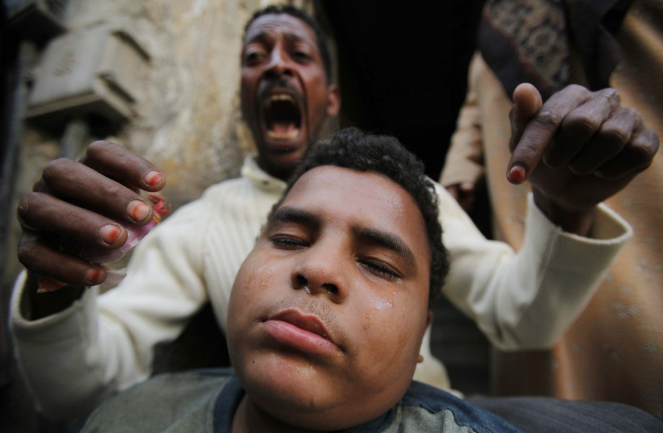 An anti-government protester reacts as his relative is injured during clashes with riot police in the port city in Suez
