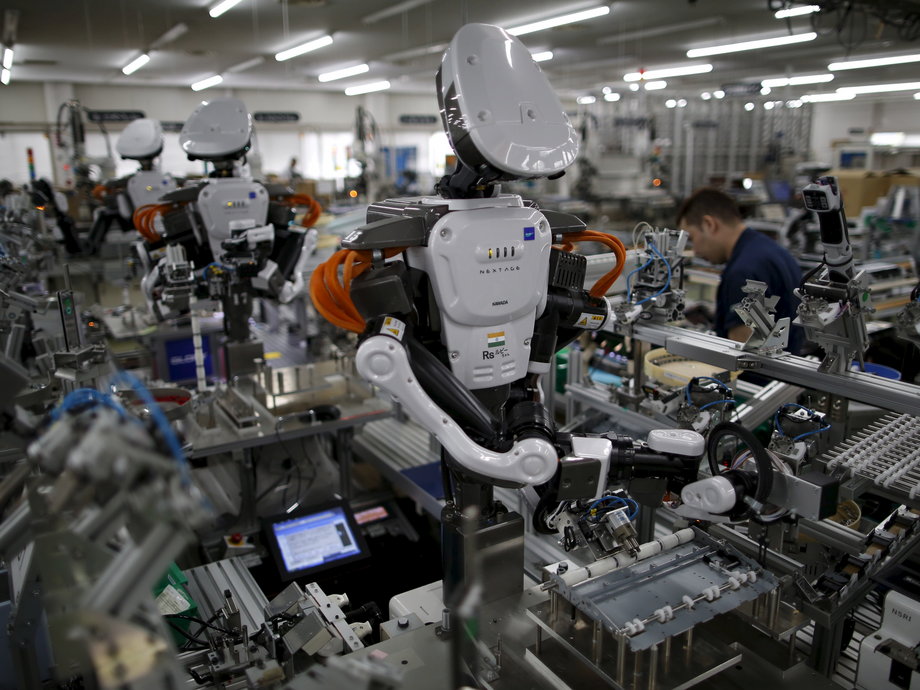 Humanoid robots working side by side with employees in the assembly line at a factory of Glory Ltd., a manufacturer of automatic change dispensers, in Kazo, north of Tokyo, in 2015.