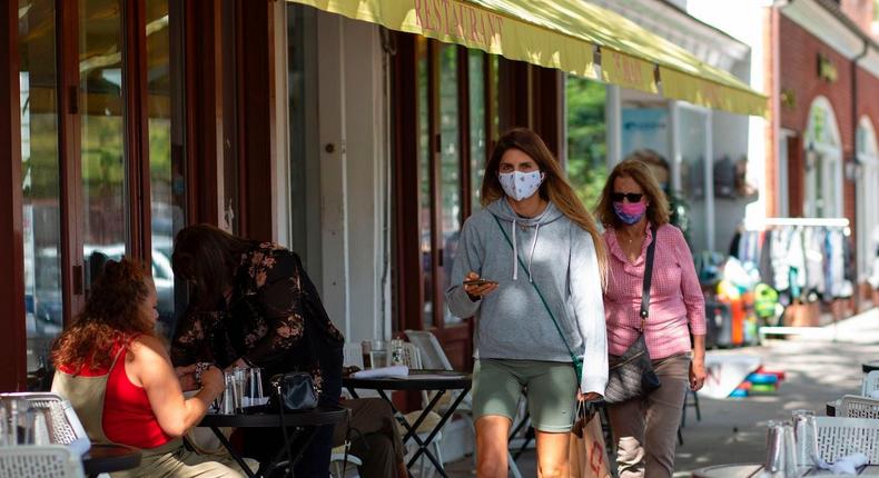 People wearing face masks walk by Main Street n Southampton, New York.
