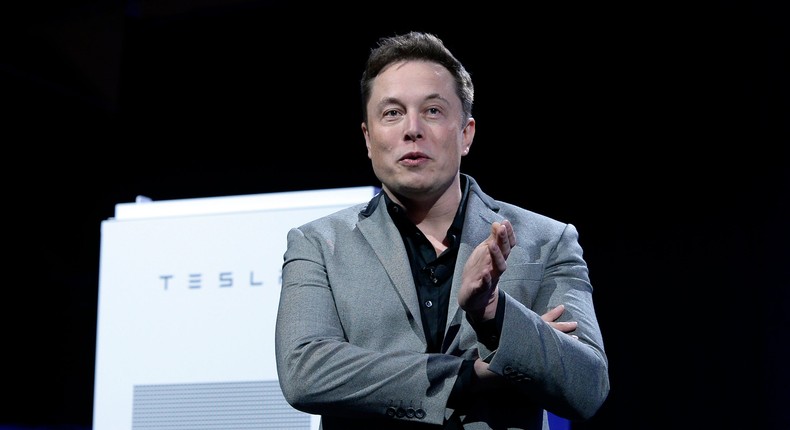 Elon Musk, CEO of Tesla, with a Powerpack unit the background unveils suit of batteries for homes, businesses, and utilities at Tesla Design Studio April 30, 2015 in Hawthorne, California
