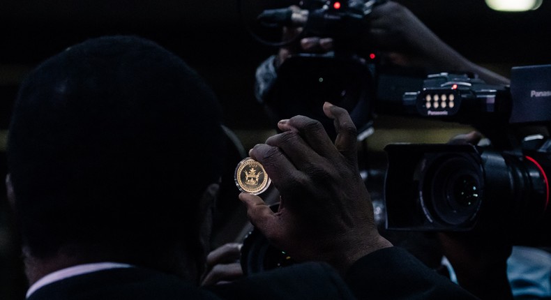 A Zimbabwe Reserve Bank staff member displays the country's new Mosi-oa-Tunya gold coin in Harare on July 25, 2022. [Photo by JEKESAI NJIKIZANA/AFP via Getty Images]