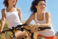 Two attractive girls on a beach with bicycles