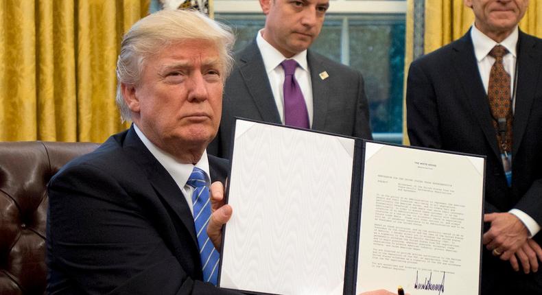 Donald Trump signing an executive order withdrawing the U.S. from the Trans-Pacific Partnership trade deal