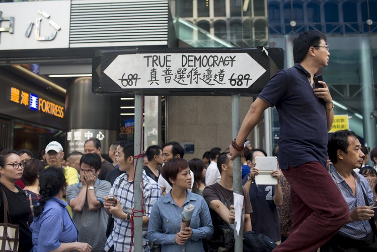 Frustracja jest szczególnie widoczna wśród przedstawicieli klasy średniej, którzy w największym stopniu zostali odcięci od zysków pochodzących z rosnącej gospodarki i których wynagrodzenie nie rosło równomiernie z cenami. <br> Na zdj. tłum obok drogowskazu wskazującego kierunek do 'prawdziwej demokracji' na Nathan Road w dzielnicy Mong Kok.