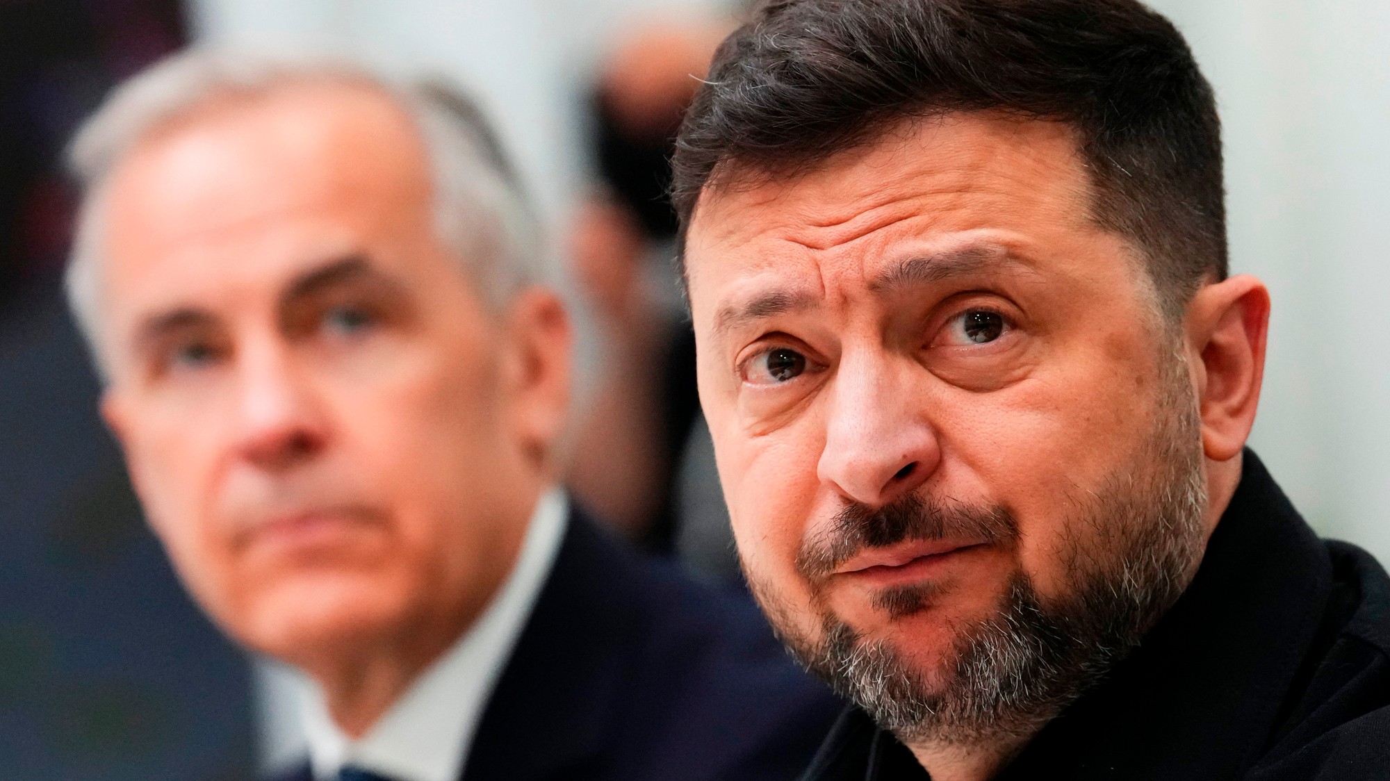 Kanadský premiér Mark Carney (v pozadí) a ukrajinský prezident Volodymyr Zelenskyj.