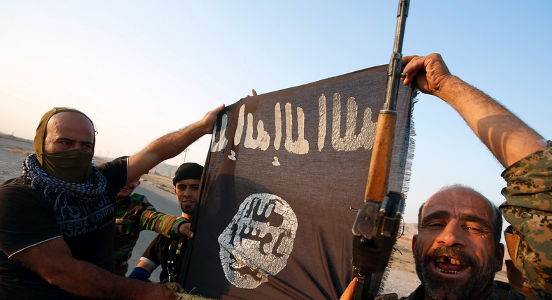 Iraqi Shiite militia fighters hold the Islamic State flag as they celebrate after breaking the siege of Amerli by Islamic State militants, September 1, 2014.