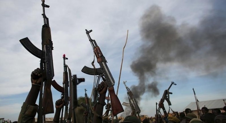 Rebel fighters hold up their rifles as they walk in front of a bushfire in a rebel-controlled territory in Upper Nile State, South Sudan February 13, 2014.    REUTERS/Goran Tomasevic