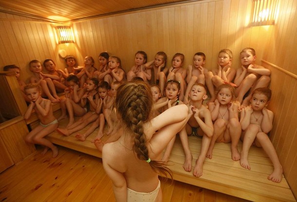 Children watch their classmates pour cold water on themselves, under the watch of fitness coach Oksa