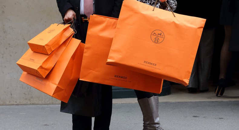 A couple walk with Hermes shopping bags as they leave an Hermes store in Paris March 21, 2013. Hermes on Thursday said operating margin last year reached its highest level since the French luxury group listed in 1993 on robust demand for its hand-crafted leather goods and printed silk scarves. REUTERS/Philippe Wojazer