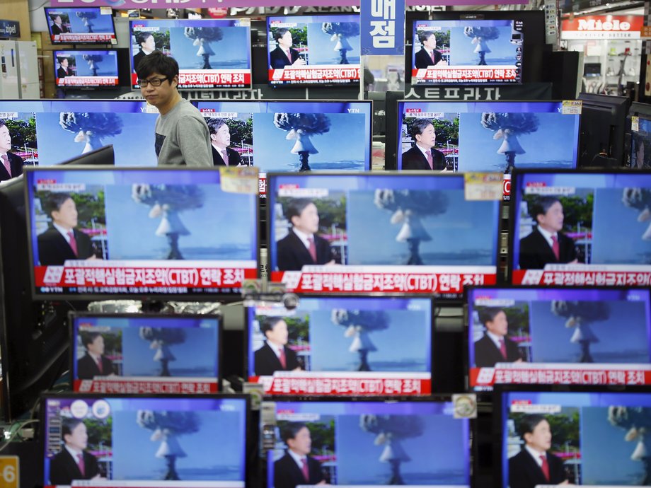 A man walks past multiple TV screens with images of North Korea's nuclear test.